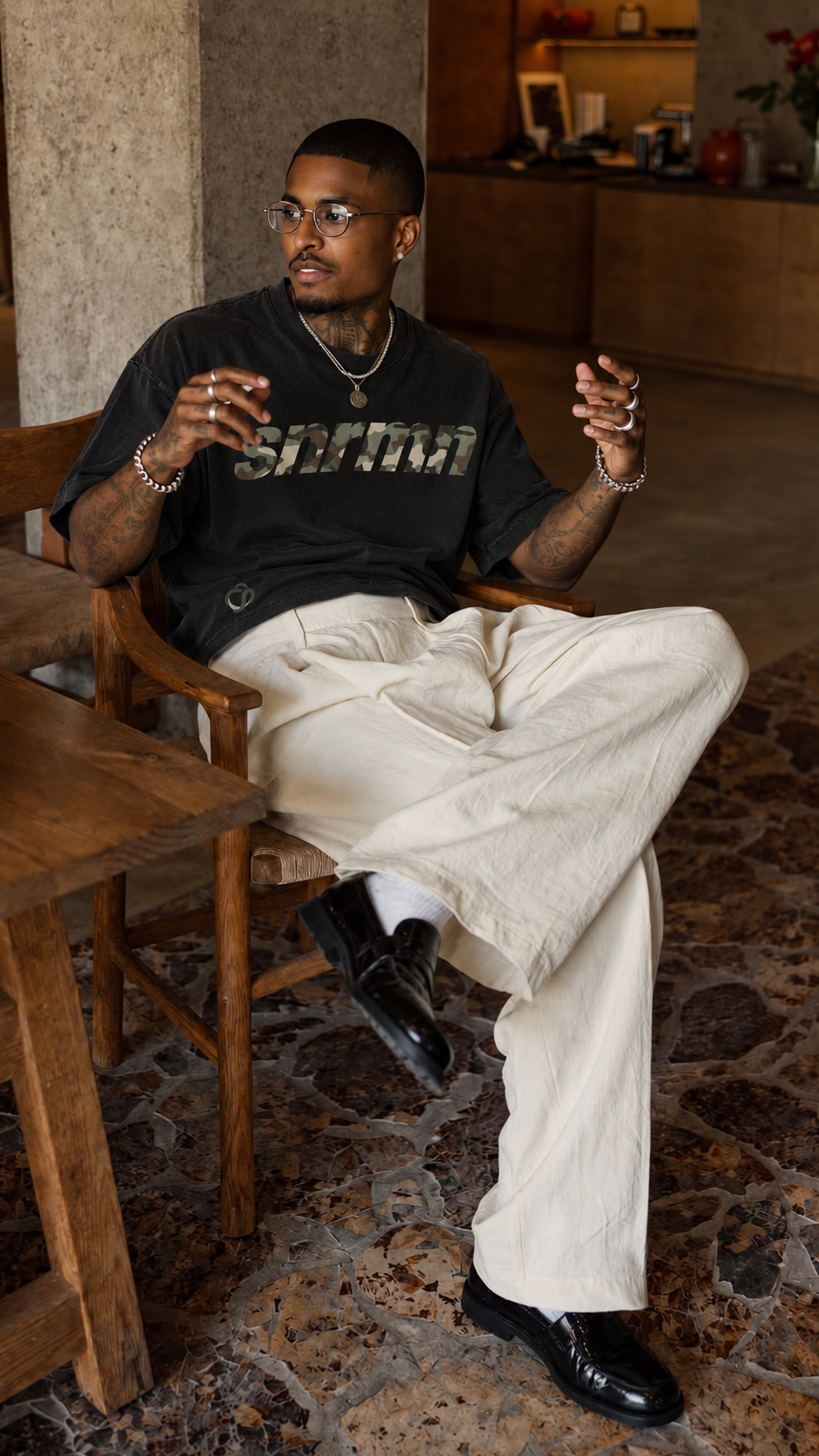 SNRMN black tee editorial seated portrait